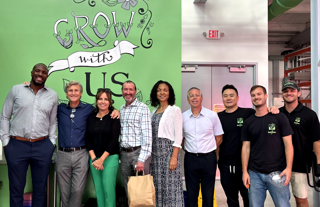 people posing for a picture in front of a wall that says "grow with us"